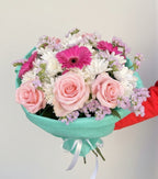 Bouquet of flowers with pink and white roses in a turquoise wrap on a light gray background
