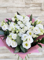 Букет от девет бели еустоми, увит в розова хартия с натурална панделка