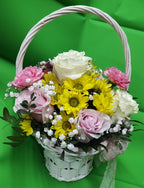 Подаръчна кошница с розови и бели рози, розови карамфили, жълти хризантеми, гипсофила и зеленина в бяла плетена кошница.