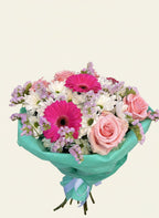 Bouquet of flowers with pink and white colors wrapped in green paper on a light beige background