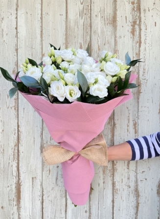 Букет от девет бели еустоми, увит в розова хартия с натурална панделка